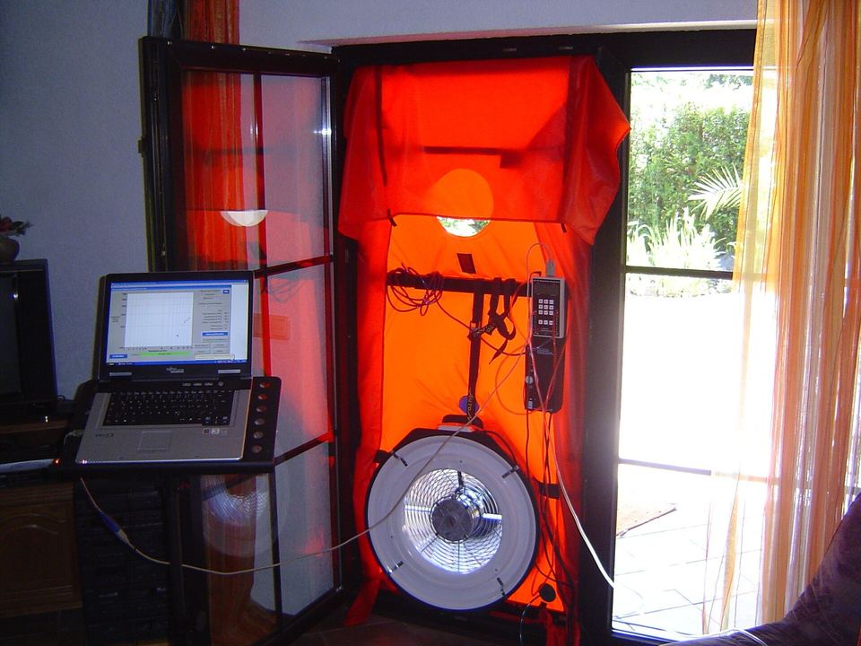 Blower door test fan in a terrace door, with a laptop recording the pressure readings