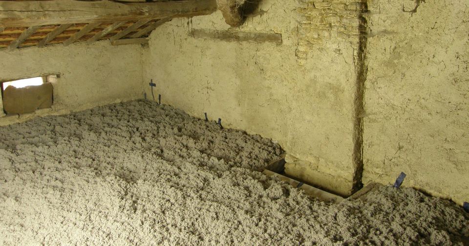 Thick layer of blown cellulose insulation covering the floor of an old attic