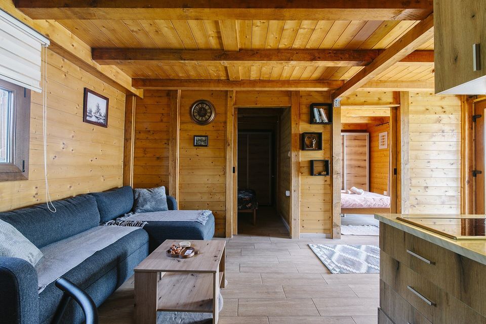 Pine-paneled living room with a blue sectional sofa, wood beams and a small coffee table
