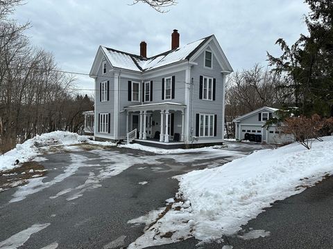 Two-story gabled farmhouse with black shutters and snowbanks along a plowed driveway