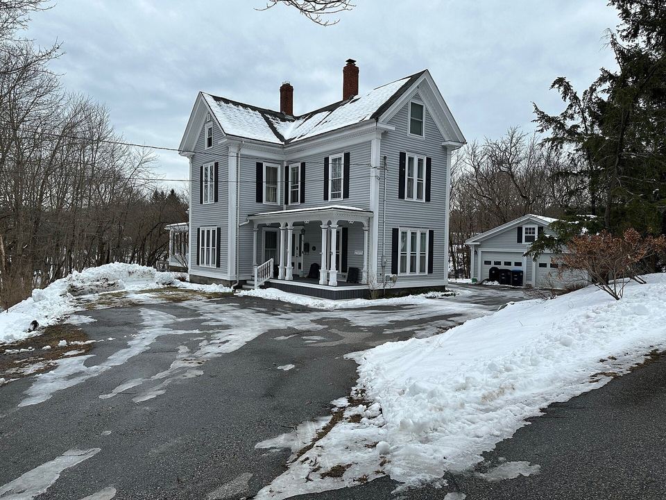 Two-story gabled farmhouse with black shutters and snowbanks along a plowed driveway
